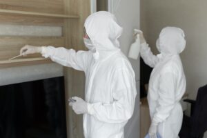 Virologists, people in protective suits carry out the disinfection in the apartment. Wipe furniture Professional cleaning restoration